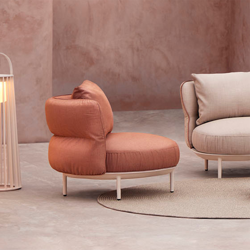 Stylish and comfortable outdoor lounge chair with plush coral-hued upholstery, complemented by a modern, minimalist design featuring a light-colored metal frame, providing a cozy yet chic seating option for an outdoor living space.