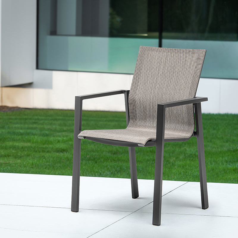 Contemporary outdoor chair with sleek gray frame and woven seat, set on a grassy surface against a glass building.