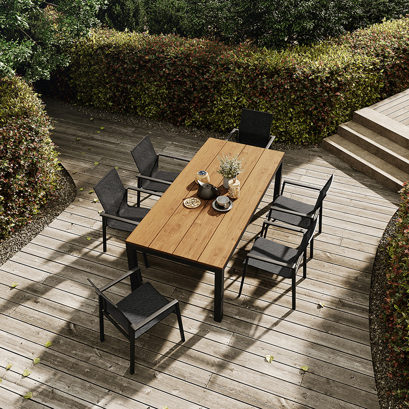 Cozy outdoor dining area with a wooden table and black chairs set on a wooden deck, surrounded by lush greenery.