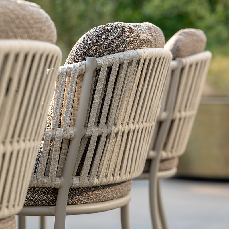This image showcases the intricate woven design and robust construction of the Outdoor Furniture chairs. The chairs feature a neutral-toned, textured fabric that complements the sleek, modern lines of the woven frame, creating a visually appealing and durable seating option for outdoor living spaces.